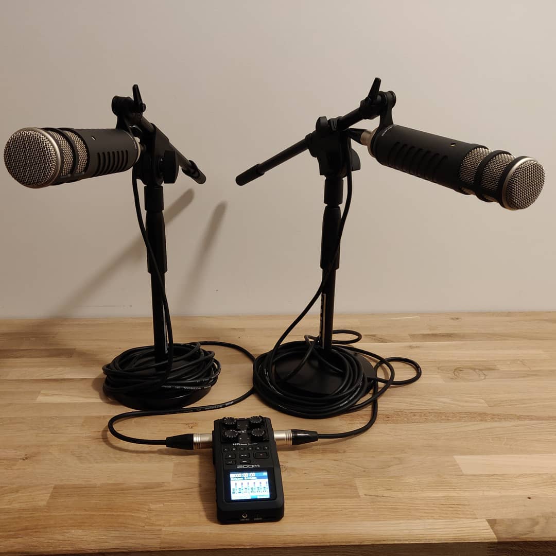 Twee podcastmicrofoons en een opnameapparaat op een bureau.