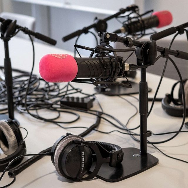 Een foto van enkele podcastmicrofoons en koptelefoons op een tafel.