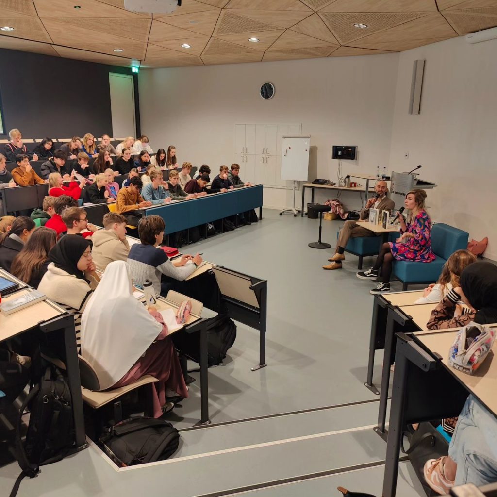 Een collegezaal vol leerlingen luistert naar Jaap Robben.