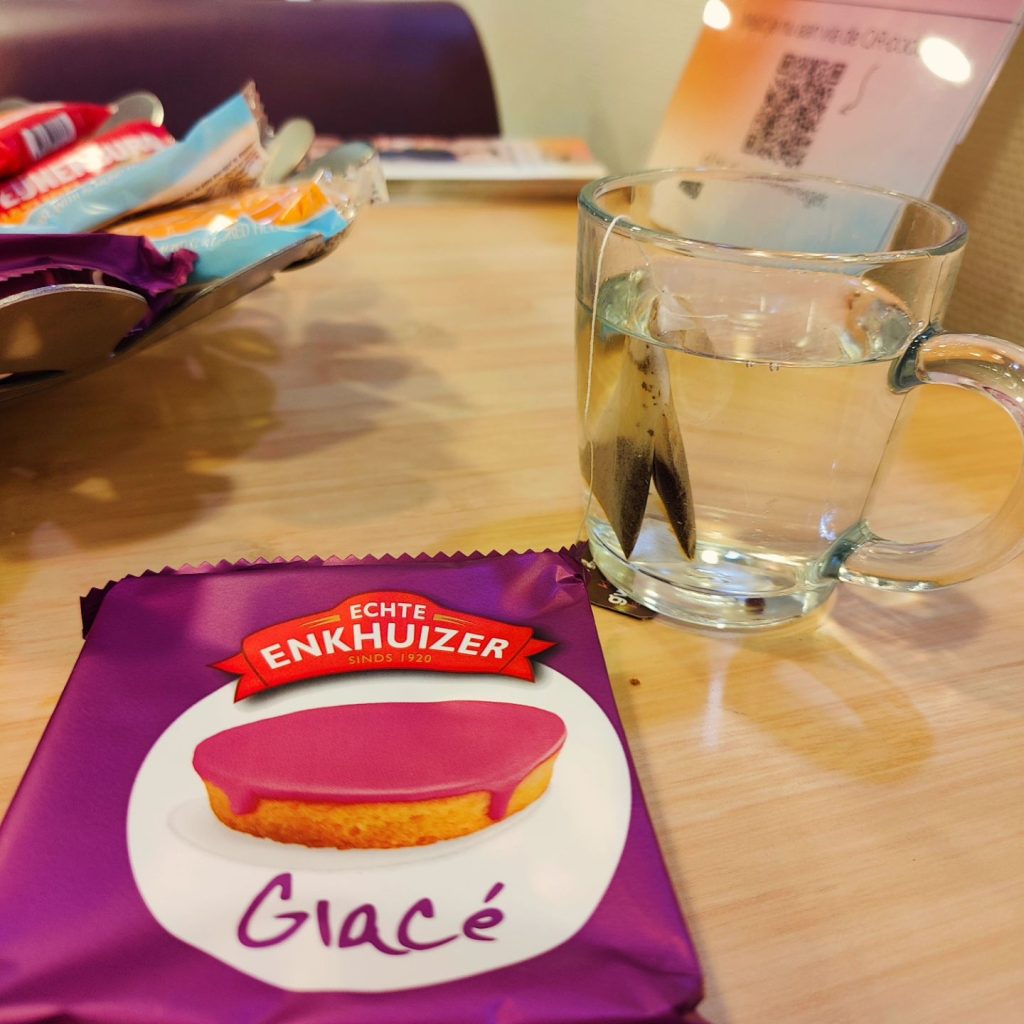 Verpakking van een roze Glacé-koek nast een glas water.